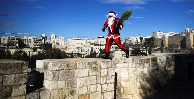 Todo un símbolo. Papa Noel, con el pino de Navidad, recorre la muralla de acceso a la ciudad vieja de Jerusalén | Foto: www.infobae.com